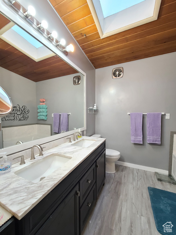 Bathroom with dual bowl vanity, a skylight, a bathing tub, wood ceiling, and wood-type flooring