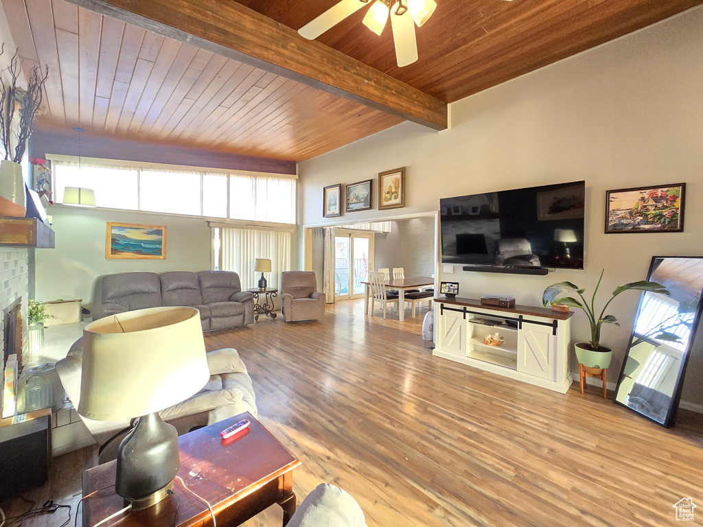 Living room with a wealth of natural light, ceiling fan, light hardwood / wood-style floors, and wooden ceiling