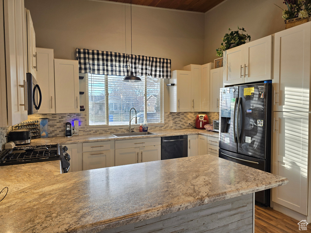 Kitchen featuring light wood-type flooring, black appliances, backsplash, and white cabinets