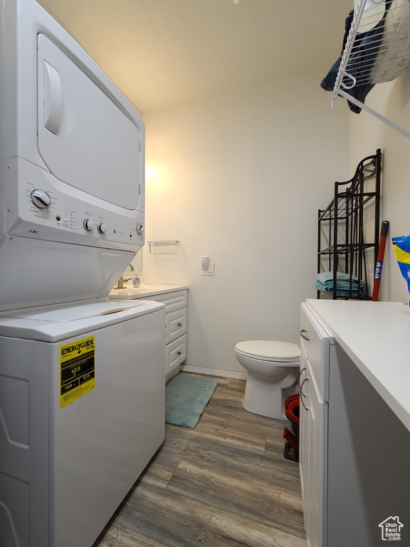 Washroom featuring dark hardwood / wood-style floors and stacked washing maching and dryer