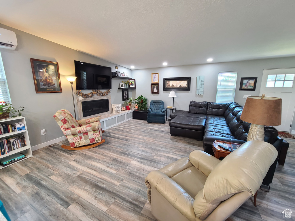 Living room featuring hardwood / wood-style flooring, a wall mounted AC, and a tile fireplace