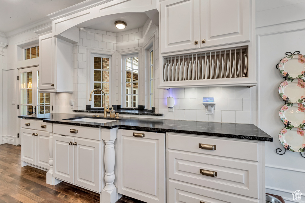 Kitchen with white cabinetry, sink, dark wood-type flooring, and tasteful backsplash
