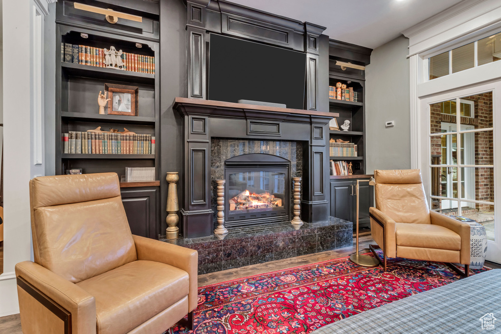 Interior space with dark hardwood / wood-style floors, built in features, and a tiled fireplace