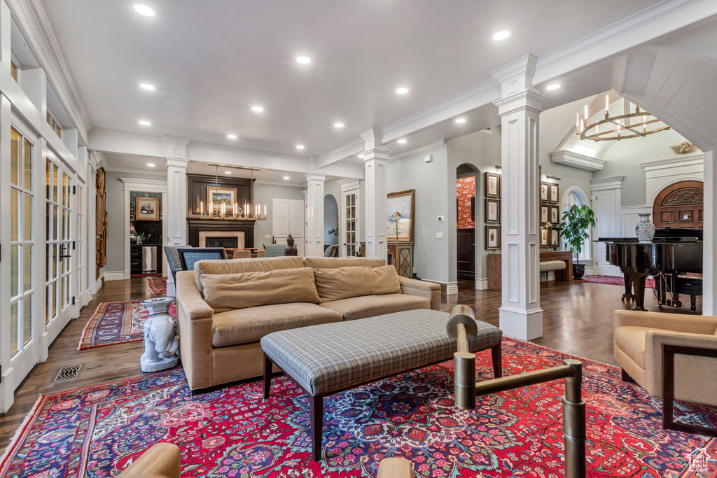 Living room featuring crown molding, dark hardwood / wood-style floors, and ornate columns