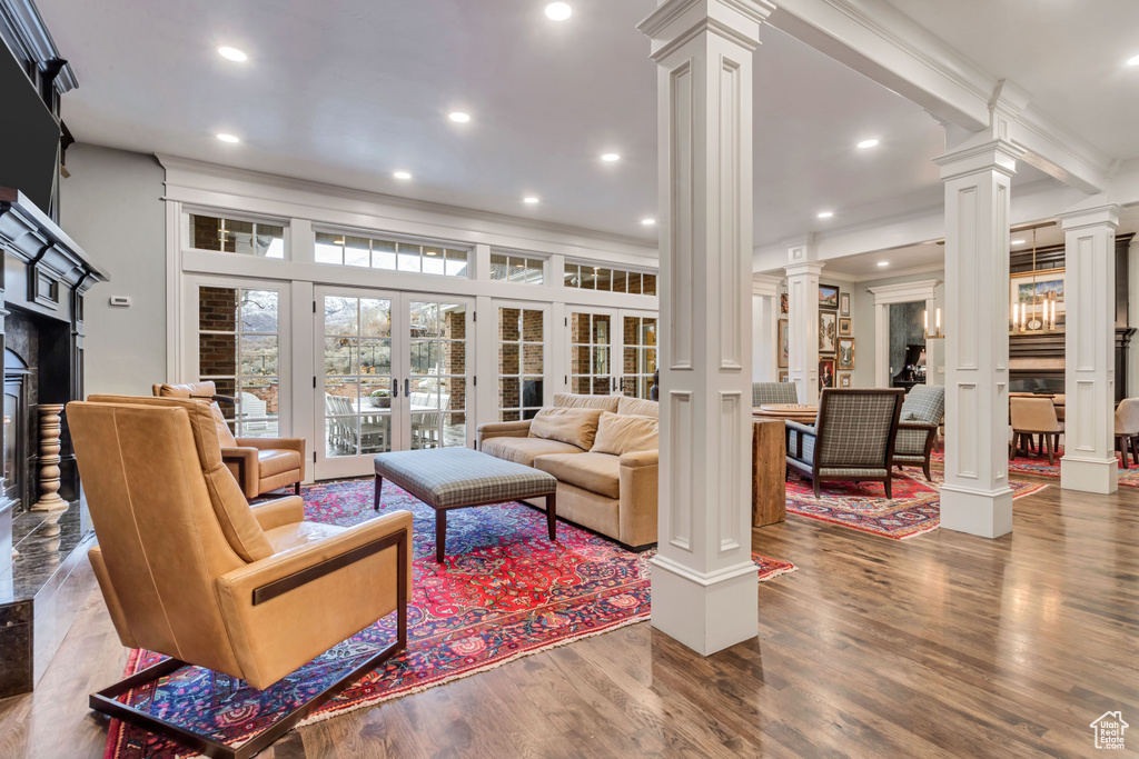 Living room featuring hardwood / wood-style floors, crown molding, and decorative columns