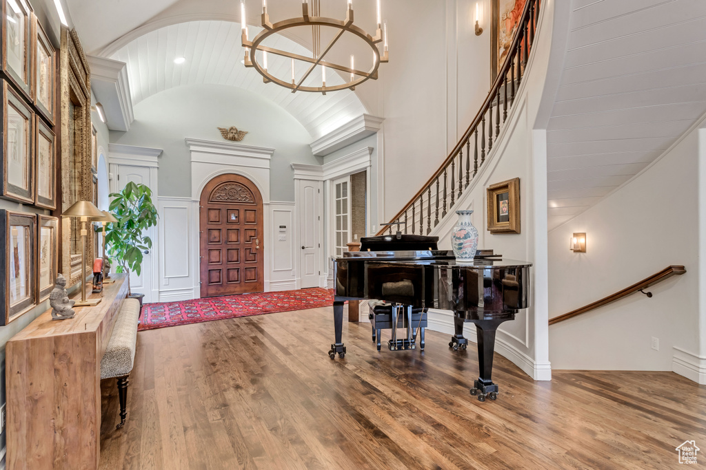 Foyer featuring wood-type flooring, a notable chandelier, and high vaulted ceiling