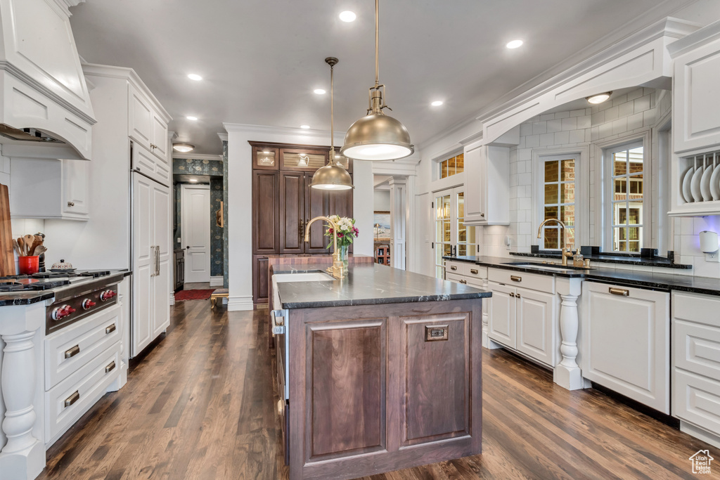 Kitchen featuring white cabinets, sink, dark wood-type flooring, and a center island with sink