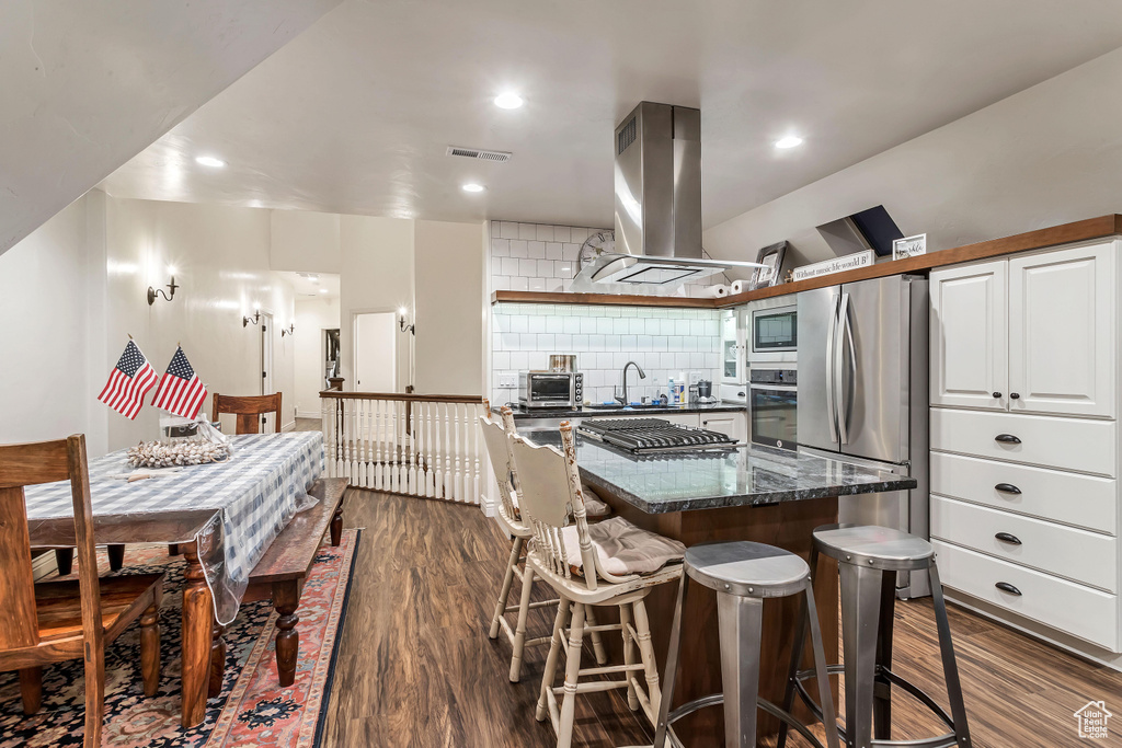 Kitchen featuring island range hood, backsplash, sink, dark hardwood / wood-style floors, and appliances with stainless steel finishes