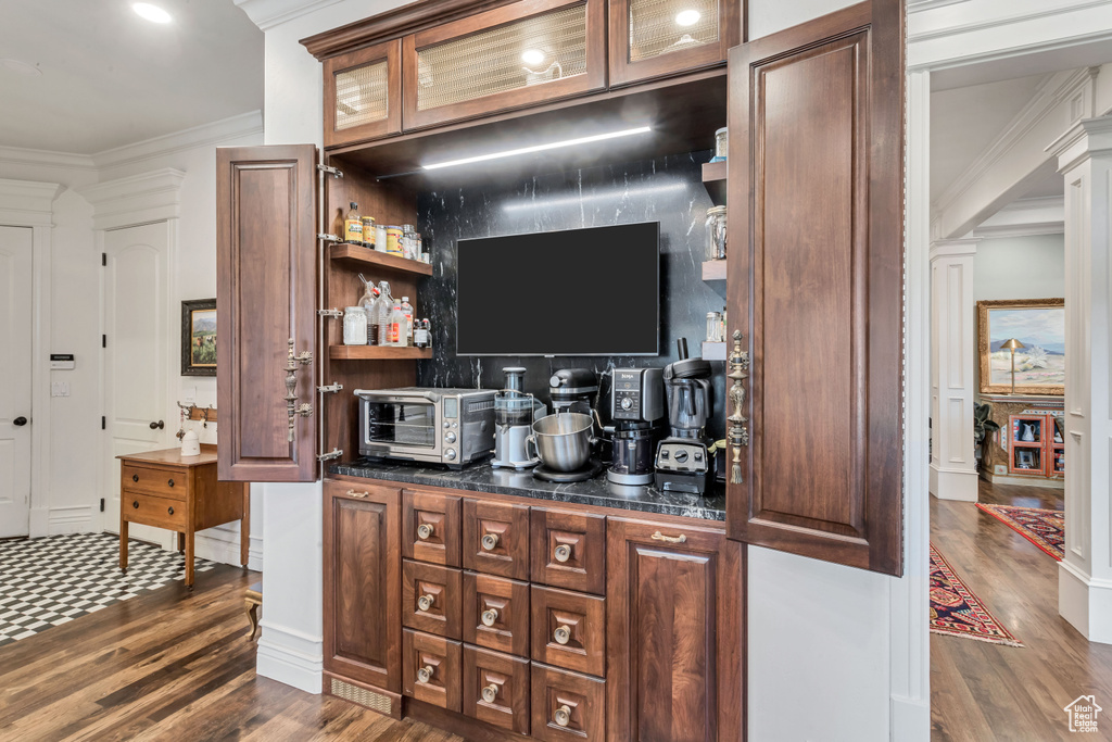 Bar featuring dark hardwood / wood-style flooring, dark brown cabinets, and ornamental molding
