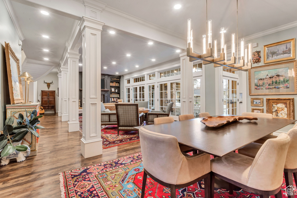 Dining space with light hardwood / wood-style flooring, crown molding, and ornate columns