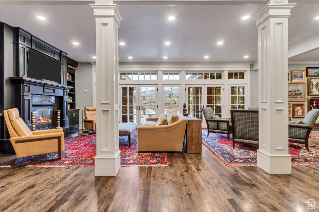 Living room with dark hardwood / wood-style floors, ornamental molding, ornate columns, and french doors