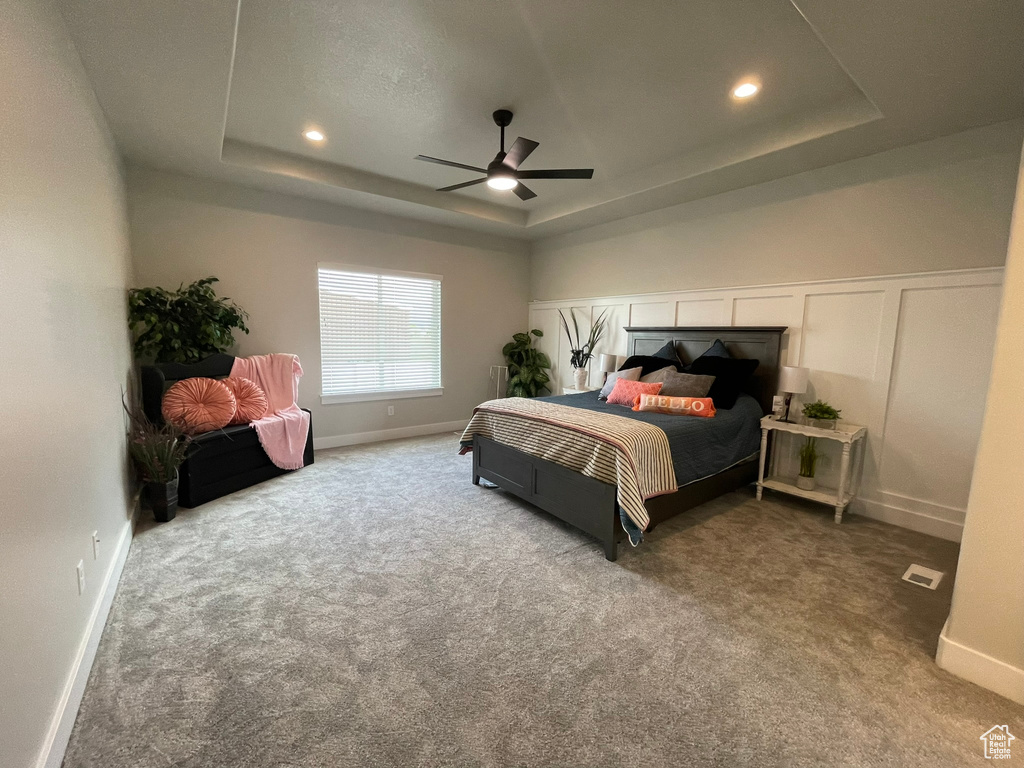 Bedroom featuring carpet, ceiling fan, and a raised ceiling
