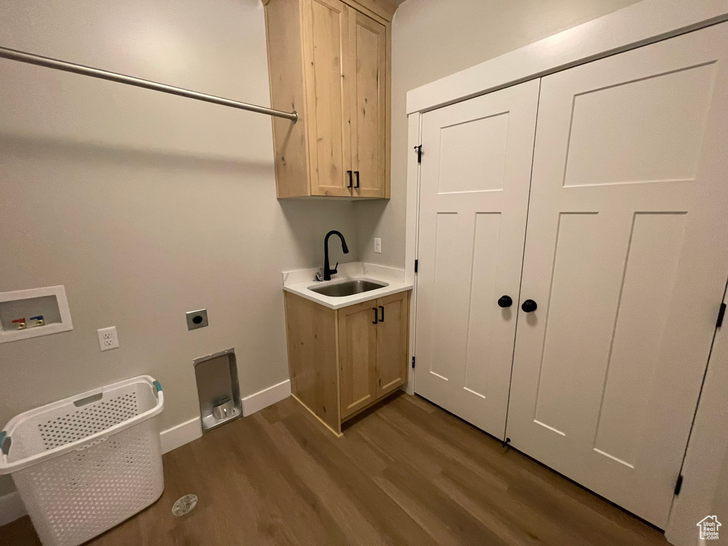 Washroom with hookup for an electric dryer, cabinets, hardwood / wood-style flooring, and sink
