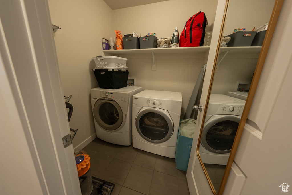 Laundry room with dark tile flooring, hookup for a washing machine, and washer and dryer