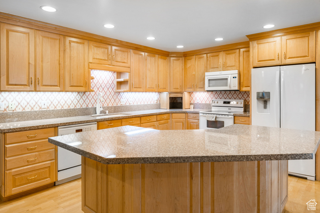 Kitchen with white appliances, light hardwood / wood-style flooring, sink, and tasteful backsplash