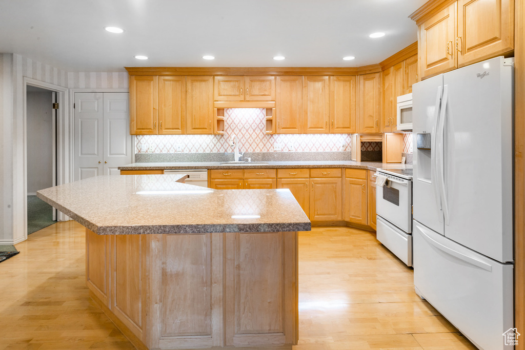 Kitchen featuring white appliances, light hardwood / wood-style flooring, and a center island