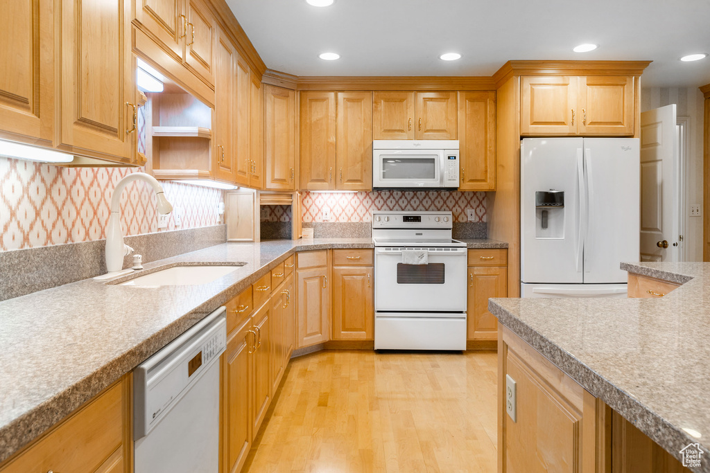 Kitchen with white appliances, sink, backsplash, and light wood-type flooring