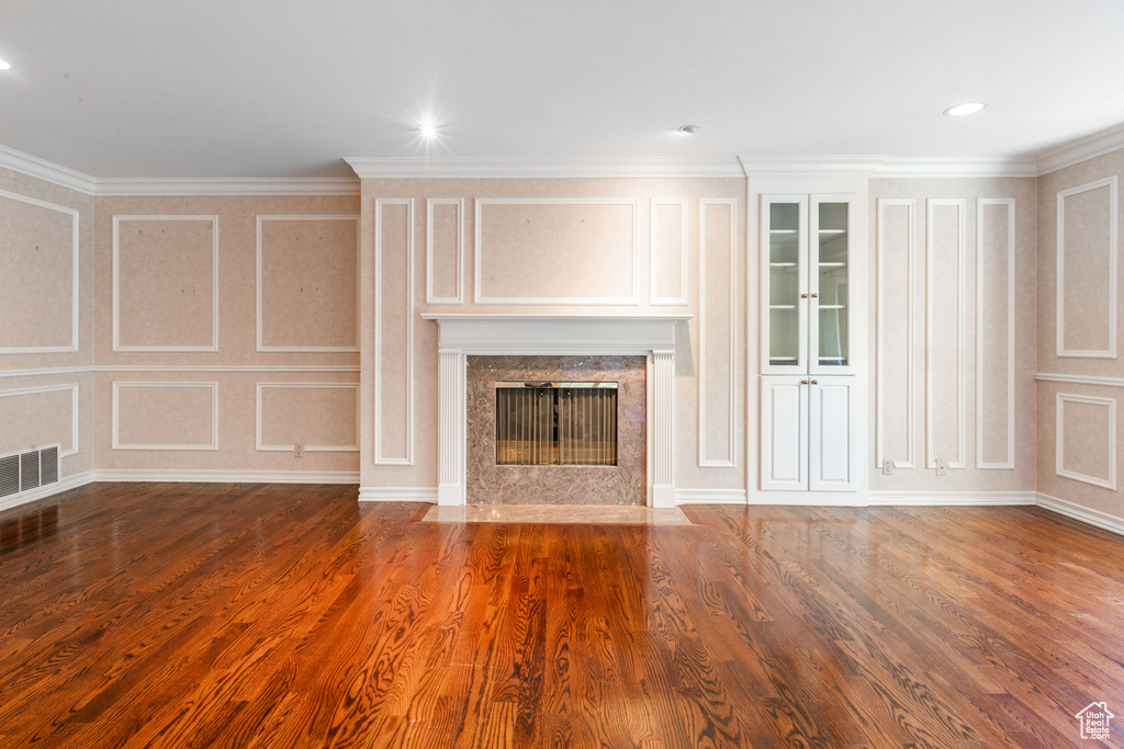 Unfurnished living room with a high end fireplace, dark wood-type flooring, and crown molding