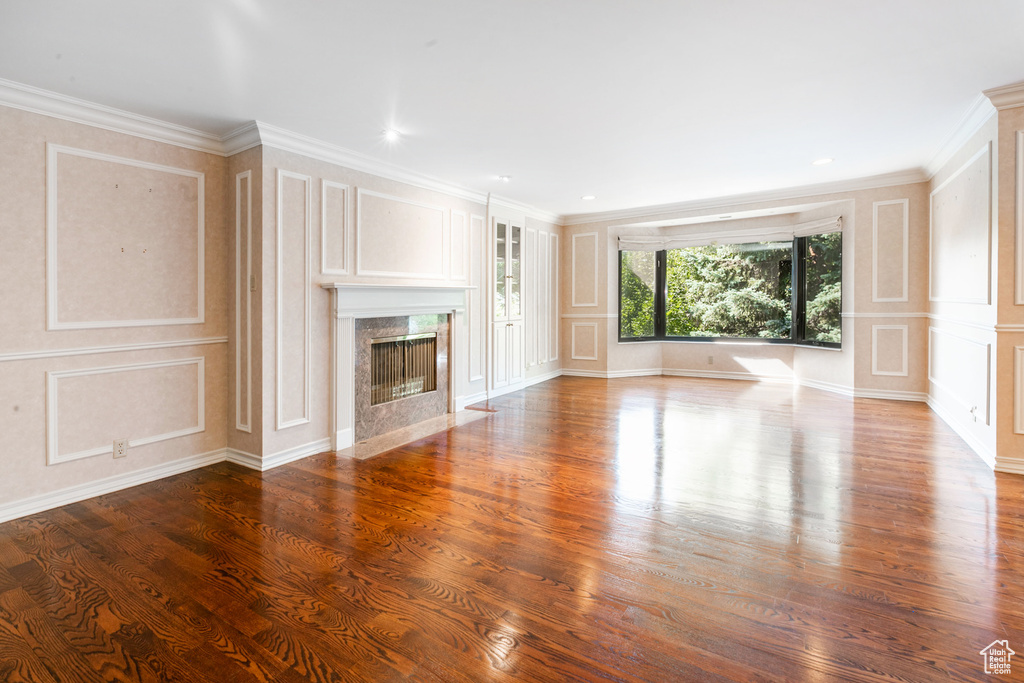 Unfurnished living room featuring a premium fireplace, dark hardwood / wood-style floors, and crown molding