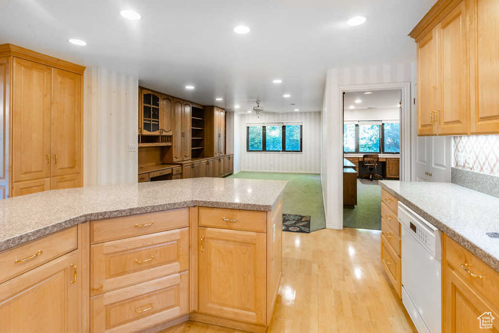 Kitchen featuring white dishwasher, ceiling fan, light brown cabinets, and light carpet