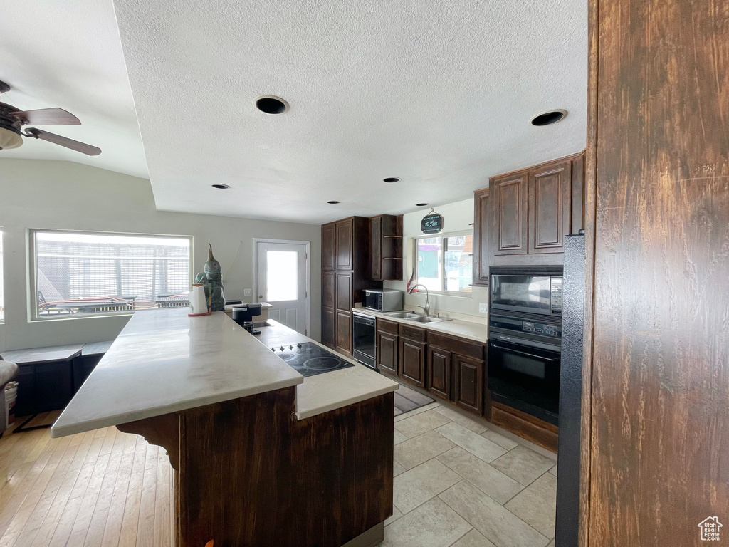 Kitchen featuring dark brown cabinets, sink, black appliances, a center island, and ceiling fan