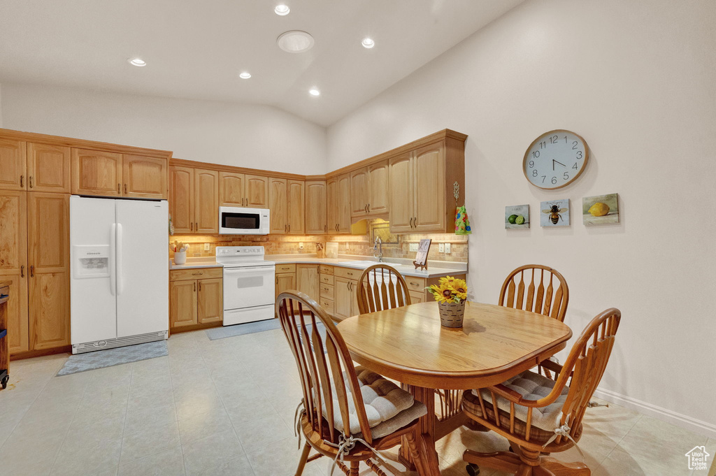 Kitchen with tasteful backsplash, sink, light tile floors, white appliances, and high vaulted ceiling