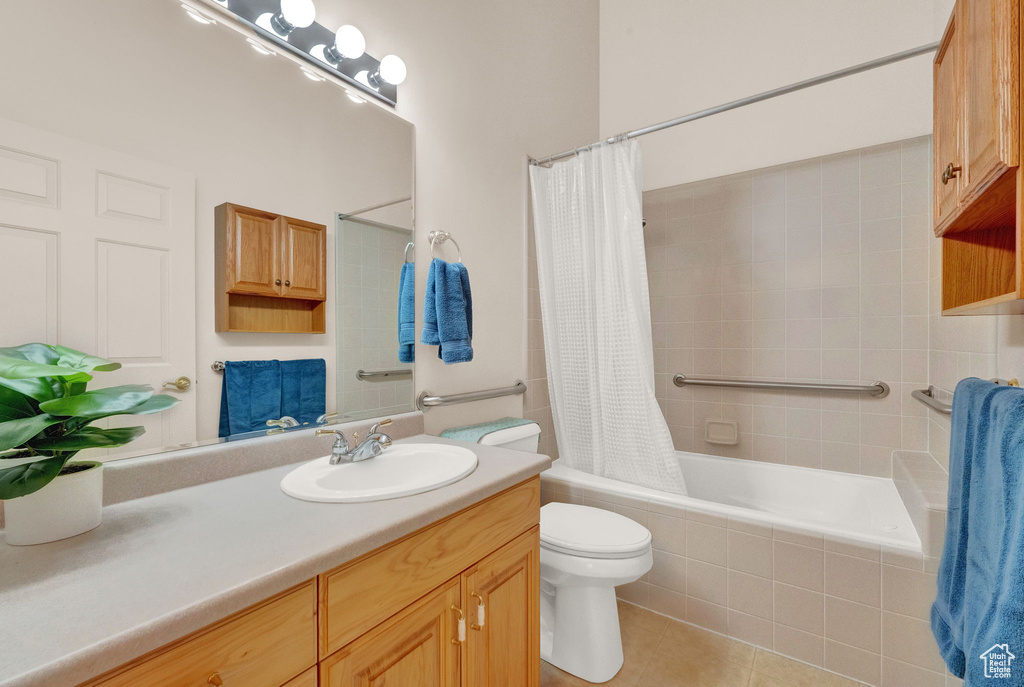 Full bathroom with large vanity, shower / tub combo, toilet, and tile flooring