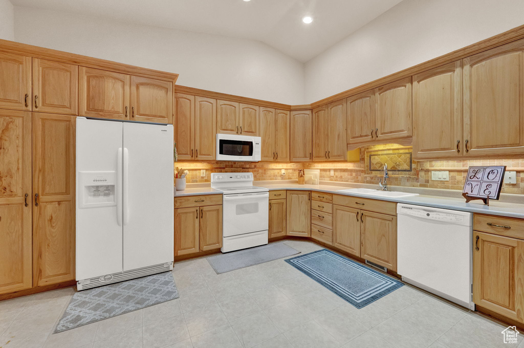 Kitchen with white appliances, light tile flooring, and sink