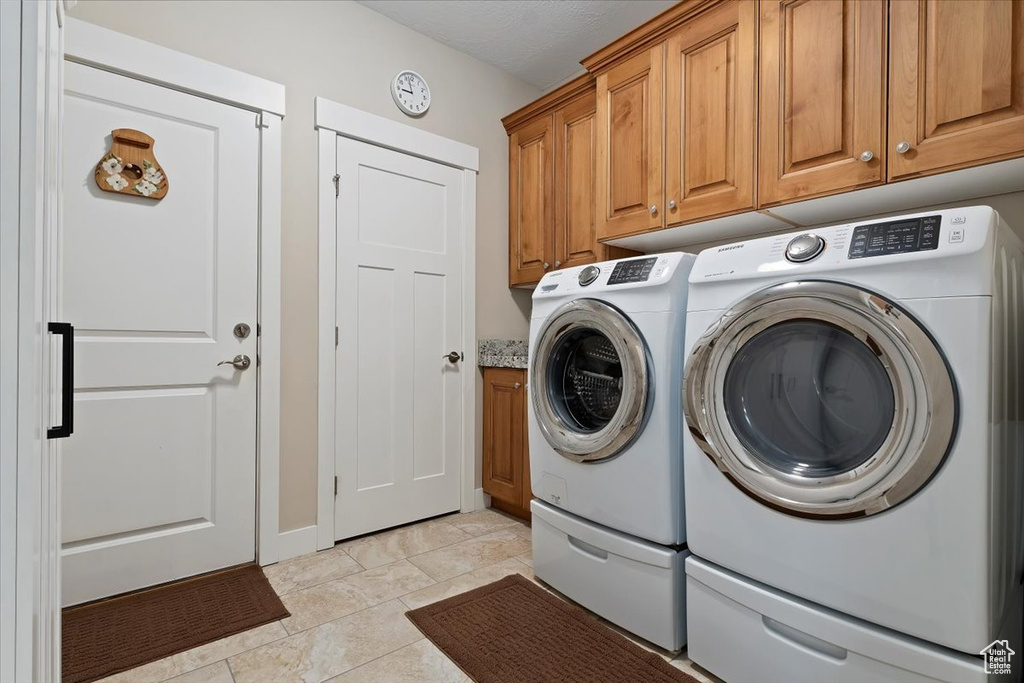 Washroom featuring light tile flooring, independent washer and dryer, and cabinets