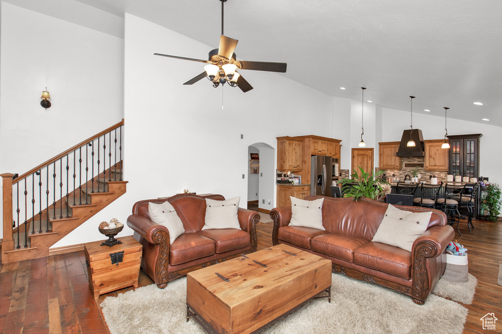 Living room with light hardwood / wood-style flooring, ceiling fan, and high vaulted ceiling