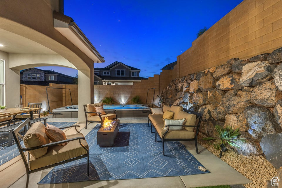 Patio terrace at twilight featuring a hot tub and an outdoor living space