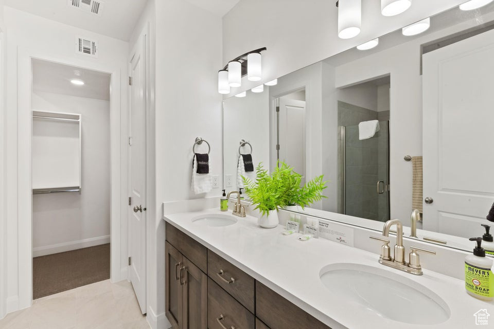 Bathroom featuring large vanity, tile floors, double sink, and an enclosed shower