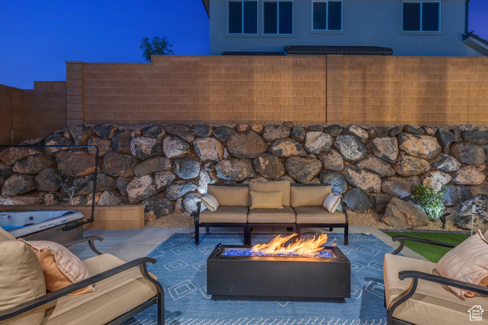 Patio terrace at night featuring an outdoor living space with a fire pit