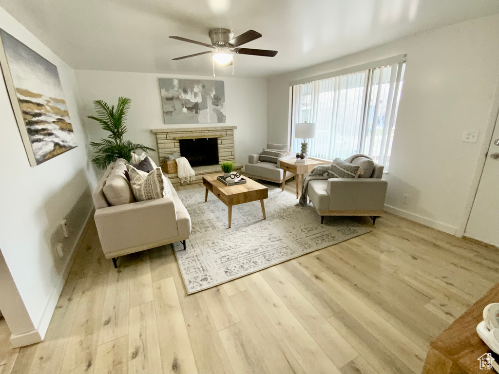Living room featuring light hardwood / wood-style flooring, a fireplace, and ceiling fan