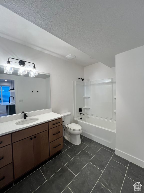 Full bathroom with a textured ceiling, vanity, toilet, tile floors, and  shower combination