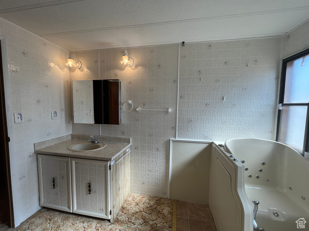 Bathroom with tile walls, a textured ceiling, vanity with extensive cabinet space, and tile flooring