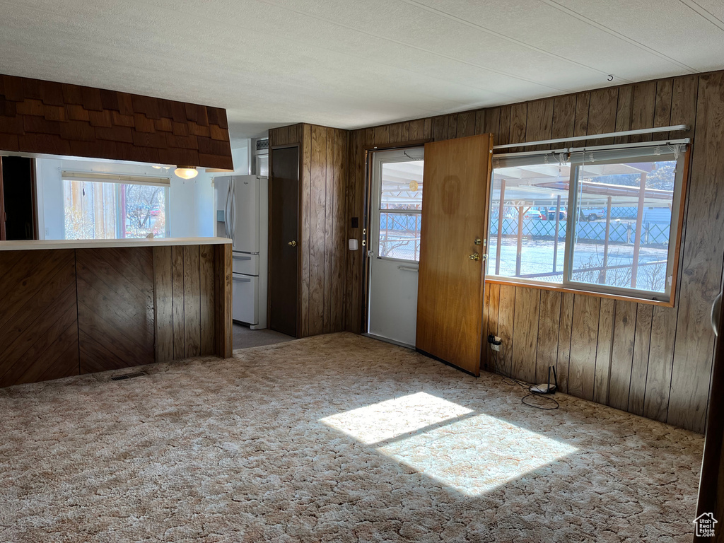 Interior space with wooden walls, light carpet, and white fridge
