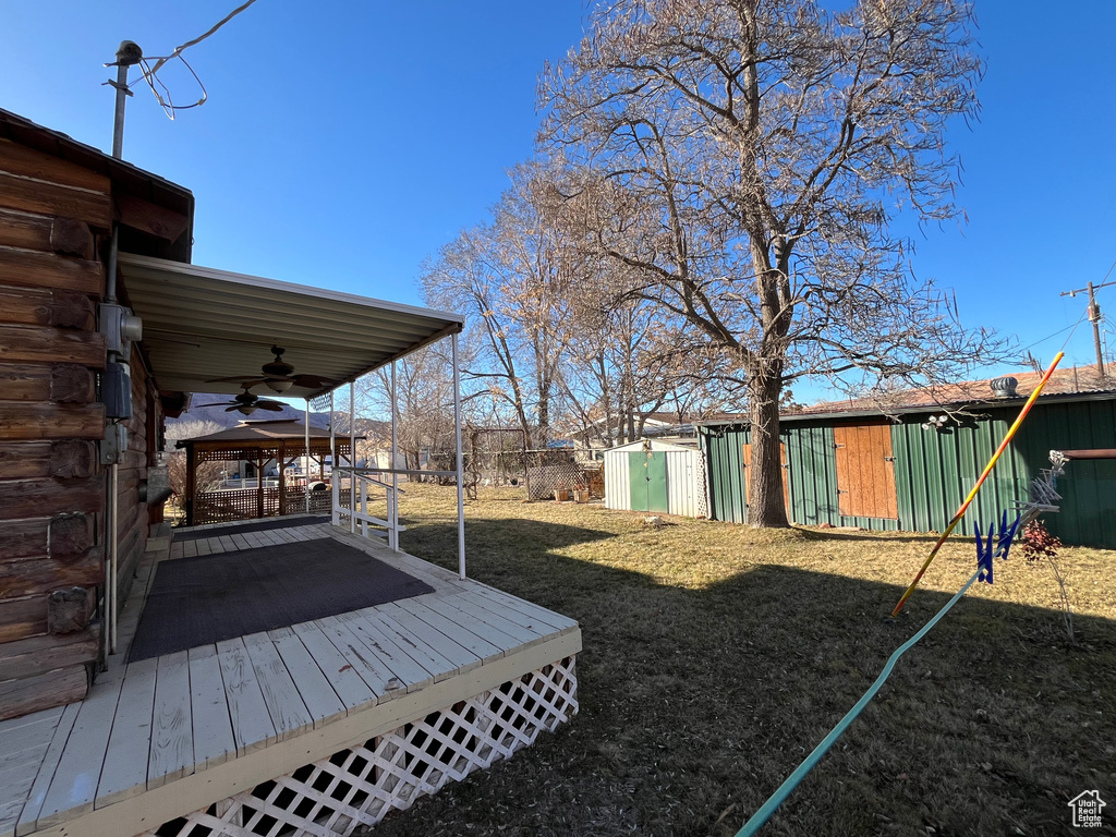 View of yard with ceiling fan and a deck