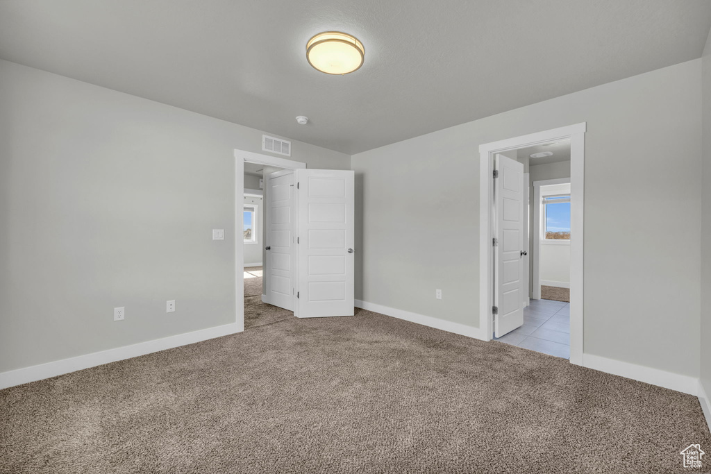 Unfurnished bedroom with light colored carpet