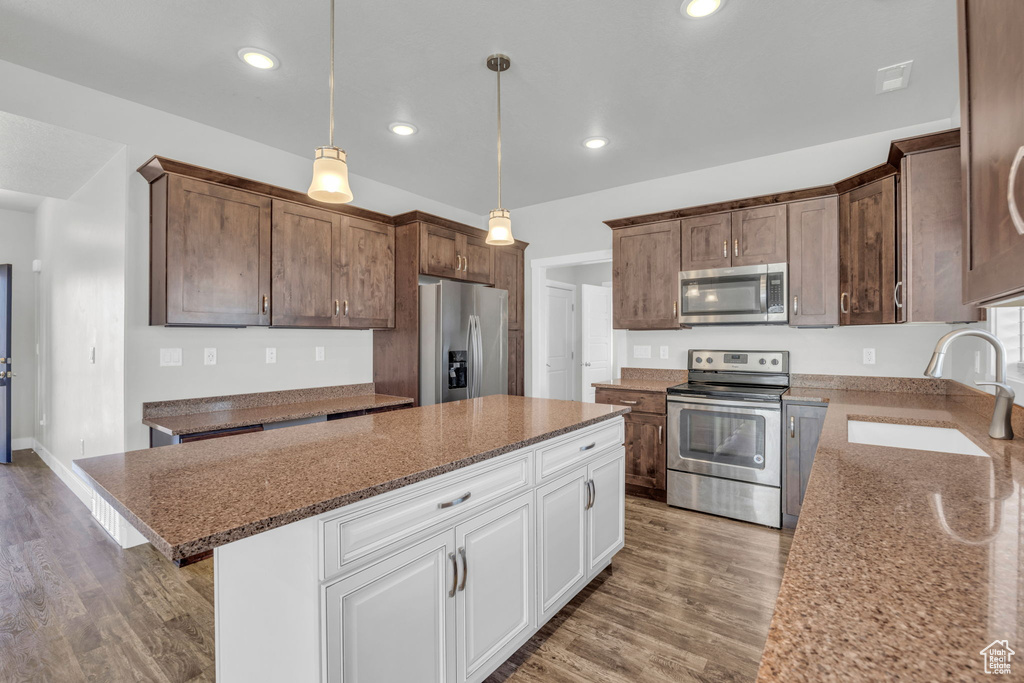 Kitchen featuring a kitchen island, sink, hardwood / wood-style flooring, appliances with stainless steel finishes, and pendant lighting