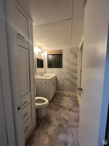 Bathroom with tile walls, vanity, tile flooring, and toilet
