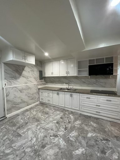 Kitchen with white cabinetry, sink, cooktop, and tile floors