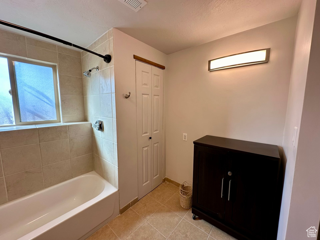 Bathroom with vanity, tiled shower / bath combo, and tile flooring