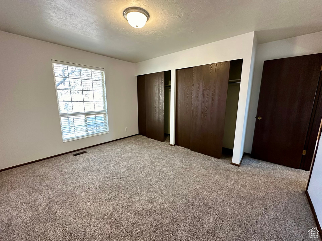 Unfurnished bedroom featuring multiple closets and light colored carpet