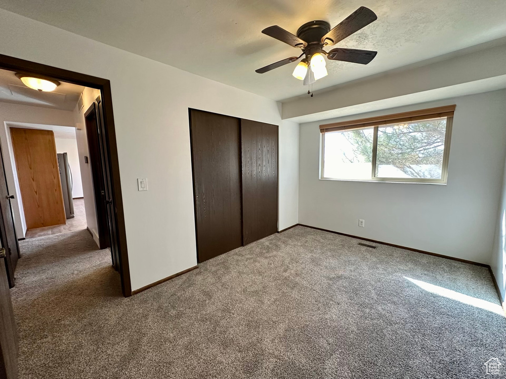 Unfurnished bedroom with carpet floors, ceiling fan, and a closet