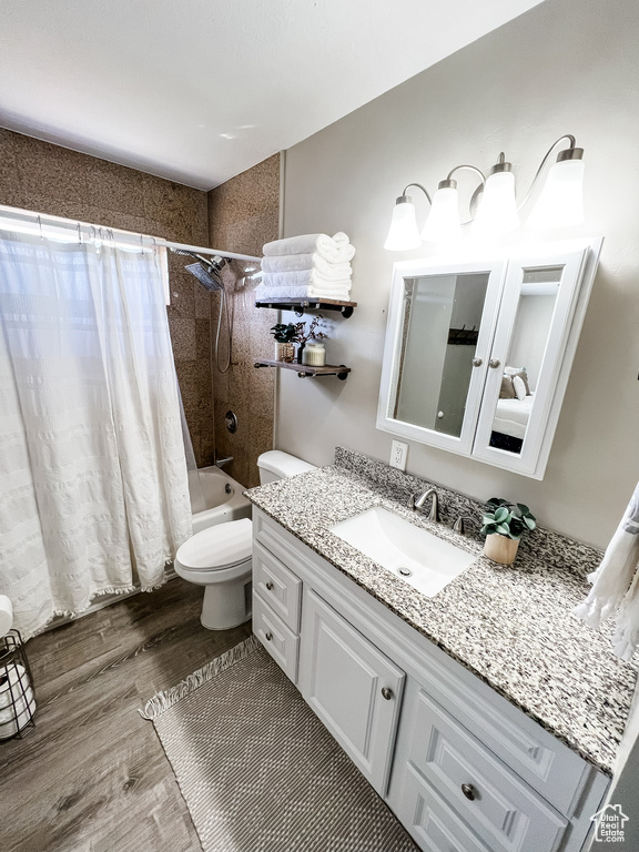 Full bathroom with wood-type flooring, vanity, shower / bath combo, and toilet