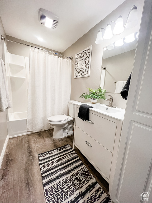 Full bathroom featuring vanity, toilet, shower / tub combo with curtain, and hardwood / wood-style flooring