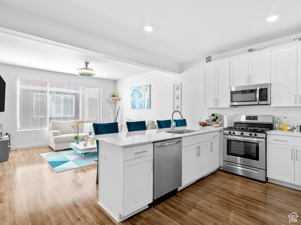 Kitchen featuring white cabinetry, light hardwood / wood-style floors, sink, and stainless steel appliances