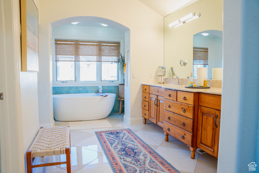 Bathroom featuring a wealth of natural light, dual sinks, tile floors, and oversized vanity