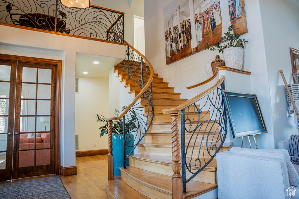 Stairway with light hardwood / wood-style flooring and french doors